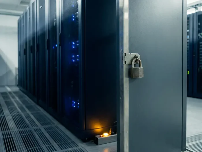 Stalen beveiligingsdeur en hangslot in moderne serverruimte met blauwe LED-verlichting en grijze metalen oppervlakken.
