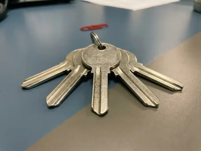 Meerdere identieke kantoorsleutels uitgewaaierd op een bureau, één zichtbaar versleten door intensief gebruik.