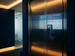 Stalen kantoordeuren met elektronisch cijferslot en reflectie van Microsoft 365-interface op geborsteld metaaloppervlak.