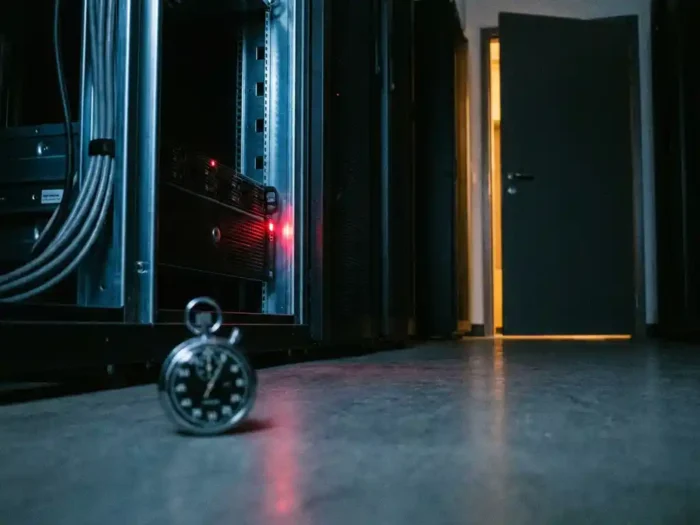 Donkere serverruimte met knipperend rood indicatielampje op rackapparaat en stopwatch op de vloer.